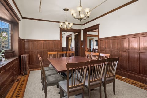 A sophisticated dining room with wood paneling and a large wooden dining table surrounded by chairs.
