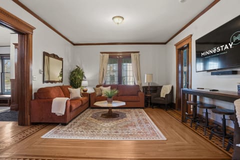 A stylish living room featuring brown sofas, a patterned rug, and accents of rich wood trim.