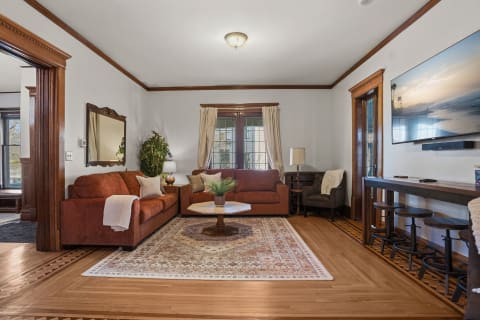 Cozy living room with two orange sofas, a coffee table, and hardwood floors.