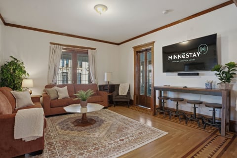 Cozy living room with plush seating, warm wood accents, and a mounted TV.