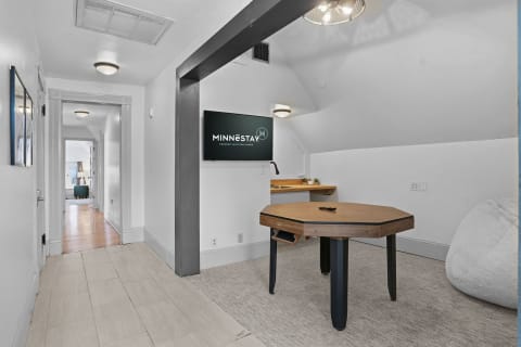 A bright game room with a wall-mounted TV and a stylish game table.