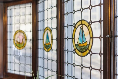 Stained glass windows depicting nautical themes with sailboats and a dolphin.