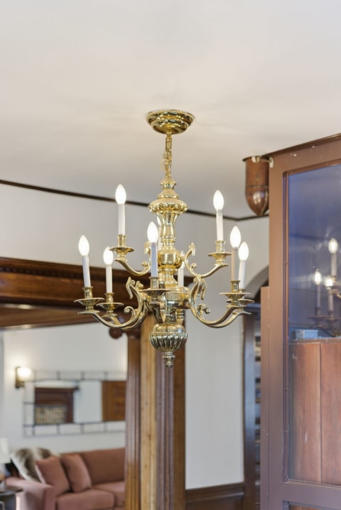 A brass chandelier with eight candle-like bulbs, emphasizing elegance in a cozy living space.
