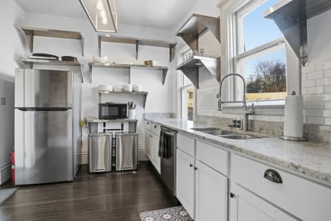 Modern kitchen with granite countertops, stainless steel appliances, and open shelving.