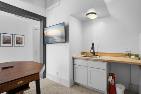 Modern game room featuring a wood countertop, gray cabinets, and a flat-screen TV with a beach scene.