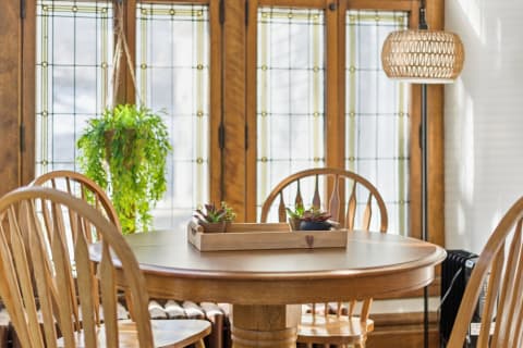 Round wooden table with succulents and wooden chairs in a sunlit room