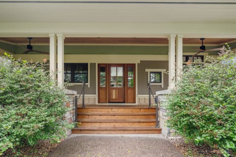 A wooden entrance with stone walls and green shrubbery leading up to double doors.
