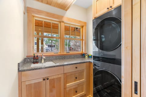Interior view of a cozy laundry room with a sink, washer and dryer, and decorative birdhouses.