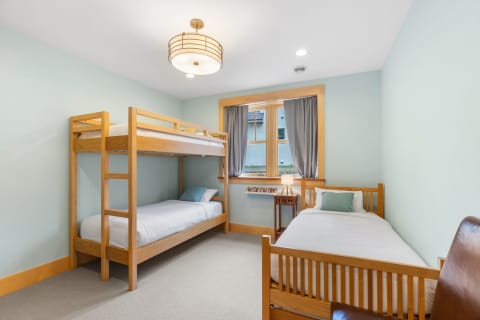 A well-decorated bedroom with a bunk bed and a single bed, featuring light blue walls and warm wooden accents.