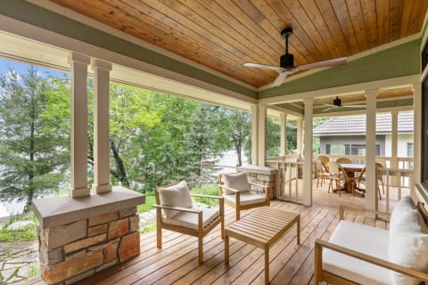 An inviting outdoor porch with wooden furniture, blending beautifully with the greenery outside.