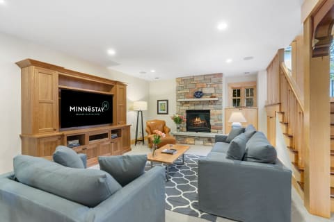 Cozy living room with a stone fireplace, modern sofas, and a decorative theme for a vacation home.