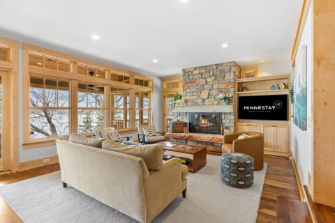 Inviting living room featuring a large stone fireplace and expansive windows.