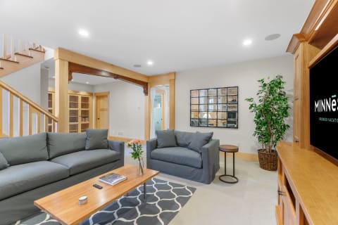 Modern living room featuring gray couches, wooden coffee table, and a decorative mirror.