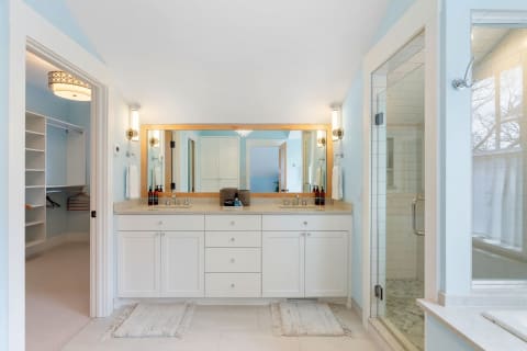 Modern bathroom with light blue walls, a spacious vanity, and a glass shower enclosure.