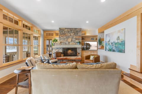 Cozy living room with stone fireplace and large windows.