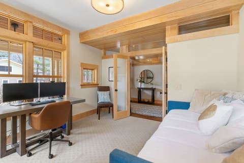 Cozy home office featuring a desk with two monitors and a comfortable couch.