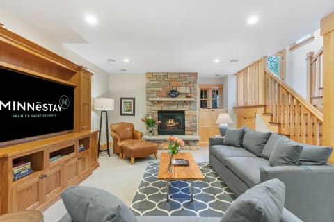 Inviting living room featuring a stone fireplace, gray sofa, and wooden furniture.