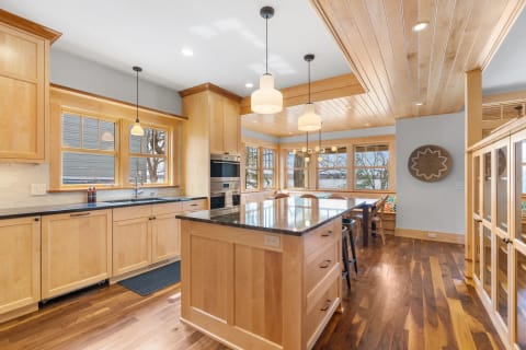 A bright kitchen with wooden cabinets, granite countertops, and ample windows.