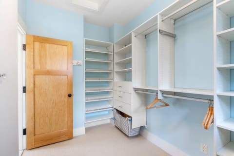 Minimalistic closet interior with blue walls and white shelves.