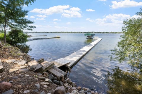 A wooden dock extends into calm lake water with a boat at the end.