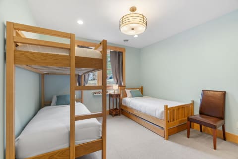 Cozy bedroom featuring a wooden bunk bed and a single bed with soft linens.