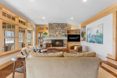 Inviting living room featuring a stone fireplace, large windows, and comfortable seating.