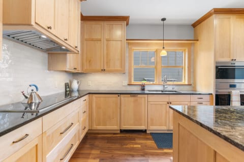 Interior view of a contemporary kitchen with wooden cabinets and granite countertops.