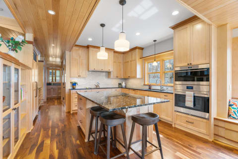 Interior view of a modern kitchen featuring light wood cabinetry and dark granite countertops.