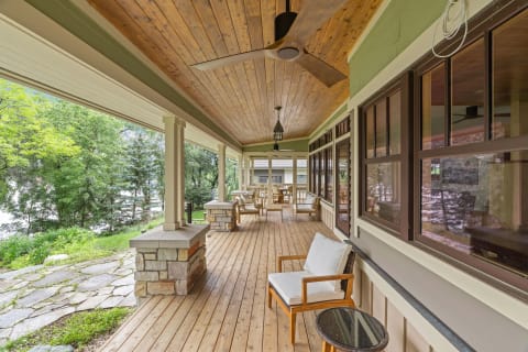 An inviting porch with wooden flooring, ceiling fan, and views of lush greenery.