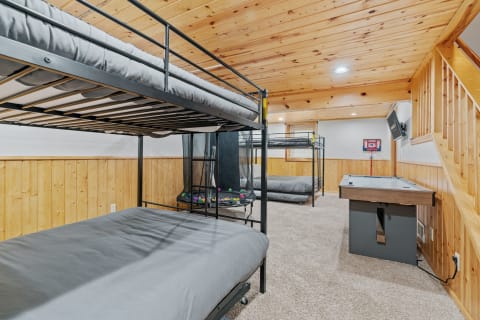 Interior view of a cozy basement room with bunk beds, a trampoline, and an air hockey table.