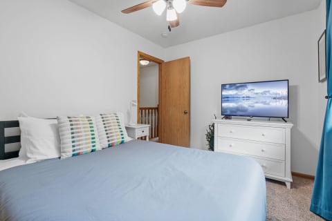 A well-decorated bedroom featuring a bed, TV, and dresser.