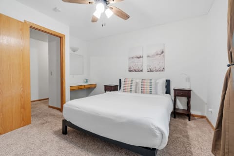 A cozy bedroom with a large bed, striped pillows, and artwork on the walls.
