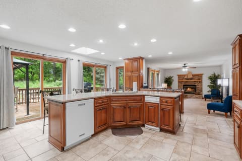 A spacious kitchen with oak cabinets and a view of greenery outside.