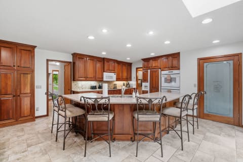 Spacious kitchen with wooden cabinets and granite countertop island.