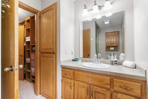Interior view of a bathroom featuring wooden cabinets and a sink with toiletries.