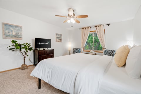 A well-decorated bedroom with a large bed, TV, and artistic accents.
