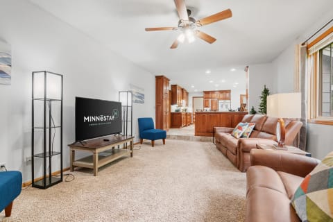 Modern living room with leather sofa, blue accent chair, and flat-screen TV.