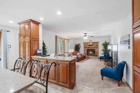 A spacious living area featuring a stone fireplace, brown leather sofa, and blue accent chairs.