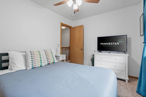 Cozy bedroom featuring a light blue comforter and colorful decorative pillows.