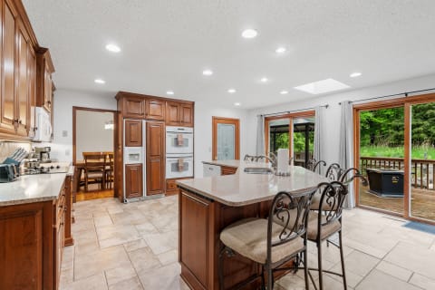 Interior view of a modern kitchen featuring wooden cabinets and a large island with seating.