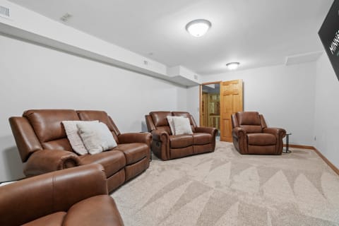 Basement lounge featuring brown leather recliners and light tan carpet.