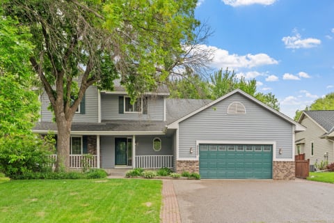 Modern two-story house with gray siding, green garage door, and lush lawn.