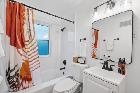 Interior view of a modern bathroom with colorful shower curtain and white vanity.