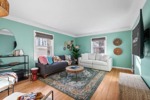 Cozy living room with mint-green walls, colorful sofas, and decorative wall art.