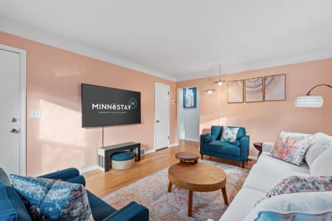 Cozy living room with blue couches, a TV, and decorative art on the peach walls.