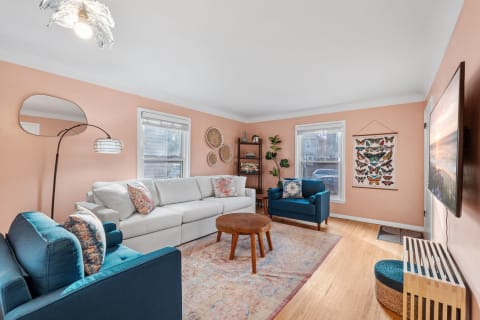 A living room featuring a light gray sectional sofa, blue chair, wooden coffee table, and butterfly decor on the walls.