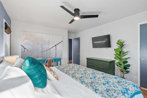 Cozy bedroom with modern decor, featuring a nature mural and stylish furnishings.