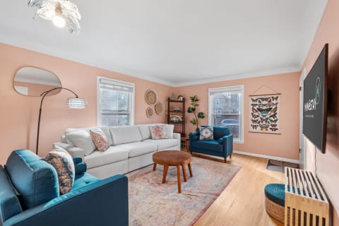 Inviting living room with a light gray sofa, teal armchair, round coffee table, and butterfly wall art.