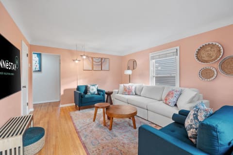 A cozy, modern living room featuring a light gray sectional, teal armchair, and decorative wall art.