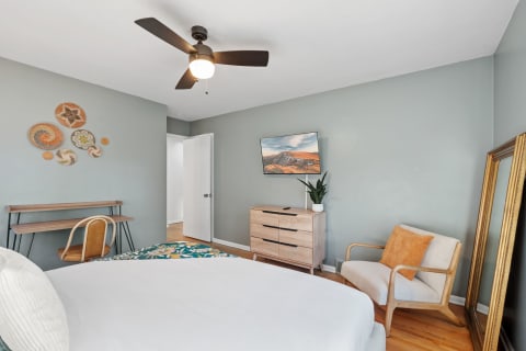 Cozy bedroom featuring a queen-sized bed, wooden furniture, and decorative wall art.